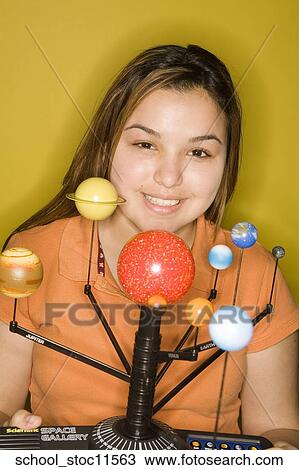 Stock Image -  Stock images of science related topics girl wearing an orange shirt showing off her solar system school project.. Fotosearch