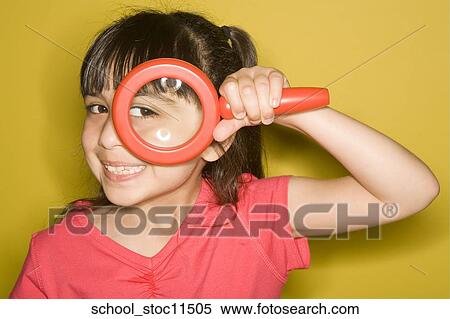 Stock Photography -  Stock images of science related topics Girl Student peers through a magnifying glass. she's wearing a pink shirt and has her hair pulled into pigtails.. Fotosearch