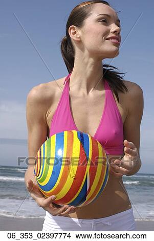 Summer BeautyWoman standing on a beach wearing a pink halterneck bikini top and white shorts holding a spiral coloured ball View Large Photo Image Picture - Summer BeautyWoman standing on a beach wearing a pink halterneck bikini top and white shorts holding a spiral coloured ball . Fotosearch