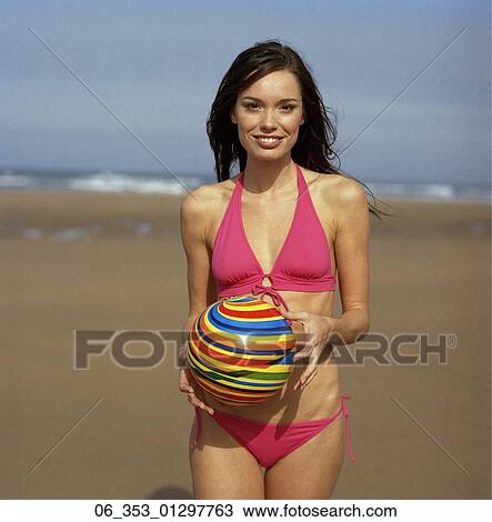 Summer BeautyWoman standing on a beach wearing a pink halterneck bikini holding a spiral coloured ball View Large Photo Image Stock Image - Summer BeautyWoman standing on a beach wearing a pink halterneck bikini holding a spiral coloured ball . Fotosearch
