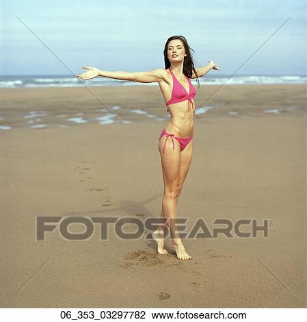 Summer BeautyWoman standing on a beach wearing a pink halterneck bikini arms outstretched View Large Photo Image Stock Image - Summer BeautyWoman standing on a beach wearing a pink halterneck bikini arms outstretched . Fotosearch