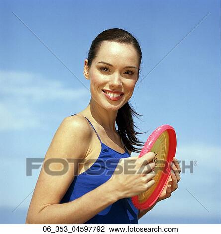 Summer BeautyWoman standing on a beach wearing a blue vest top holding red and yellow frisbee  View Large Photo Image Stock Image - Summer BeautyWoman standing on a beach wearing a blue vest top holding red and yellow frisbee . Fotosearch