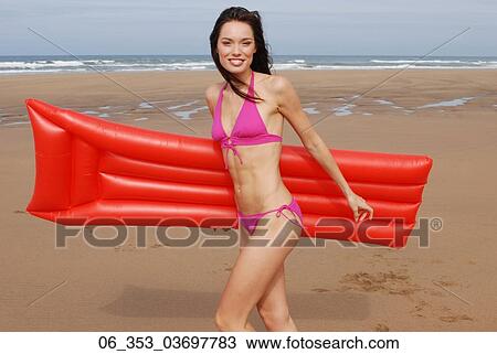 Summer BeautyWoman wearing a pink halterneck bikini running on the beach holding a red lilo View Large Photo Image Stock Image - Summer BeautyWoman wearing a pink halterneck bikini running on the beach holding a red lilo . Fotosearch