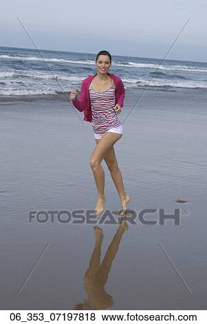 Stock Photo - Summer BeautyWoman wearing a stripey vest top cardigan and white hotpants shorts running on the beach . Fotosearch