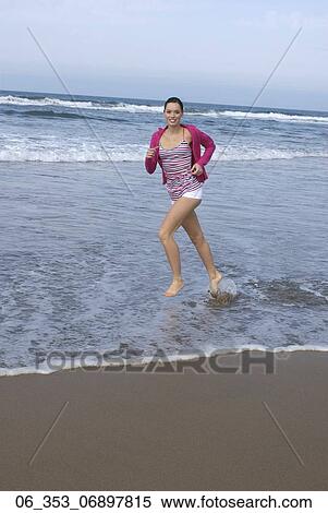 Stock Photography - Summer BeautyWoman wearing a stripey vest top white hotpants shorts and cardigan running on the beach . Fotosearch