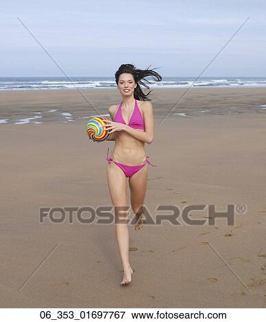 Summer FitnessWoman wearing a pink halterneck bikini running with a spiral coloured ball in her hands View Large Photo Image Stock Photo - Summer FitnessWoman wearing a pink halterneck bikini running with a spiral coloured ball in her hands. Fotosearch