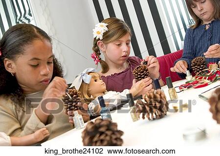 Three young girls decorating pine cones one girl holds a doll View Large Photo Image Stock Image - Three young girls decorating pine cones one girl holds a doll. Fotosearch