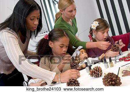 Two young girls and their mothers decorating pine cones. View Large Photo Image Stock Image - Two young girls and their mothers decorating pine cones.. Fotosearch