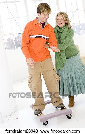 Woman and a teenage boy standing in front of a window. The boy is on a skateboard and the woman has her hands on his side. View Large Photo Image Stock Photo - Woman and a teenage boy standing in front of a window. The boy is on a skateboard and the woman has her hands on his side.. Fotosearch