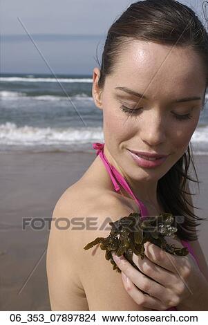 Woman BeachWoman standing on a beach wearing a pink halterneck bikini holding seaweed View Large Photo Image Picture - Woman BeachWoman standing on a beach wearing a pink halterneck bikini holding seaweed . Fotosearch