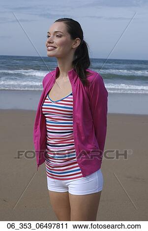 Woman BeachWoman standing on a beach wearing a stripey vest top white hotpant shorts pink cardigan with her arms behind her back View Large Photo Image Stock Image - Woman BeachWoman standing on a beach wearing a stripey vest top white hotpant shorts pink cardigan with her arms behind her back . Fotosearch