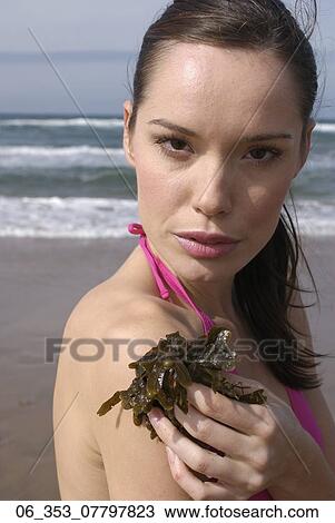 Woman BeachWoman standing on a beach wearing a pink halterneck bikini holding seaweed View Large Photo Image Stock Image - Woman BeachWoman standing on a beach wearing a pink halterneck bikini holding seaweed . Fotosearch