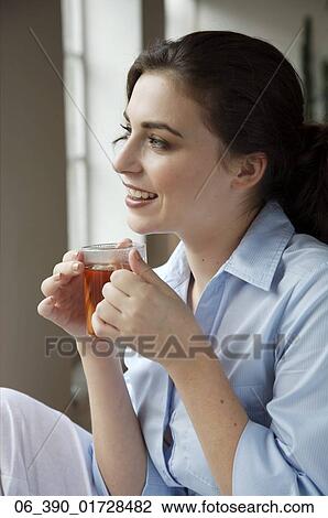 Woman DrinkingCropped shot of a woman wearing a blue shirt drinking from a glass mug View Large Photo Image Stock Image - Woman DrinkingCropped shot of a woman wearing a blue shirt drinking from a glass mug . Fotosearch