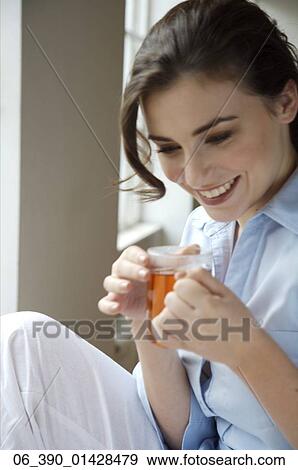 Woman DrinkingCropped shot of a woman wearing a blue shirt drinking from a glass mug View Large Photo Image Stock Photo - Woman DrinkingCropped shot of a woman wearing a blue shirt drinking from a glass mug . Fotosearch