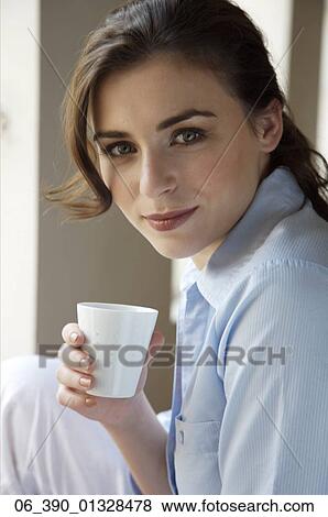 Woman DrinkWoman wearing a blue shirt holding a white cup View Large Photo Image Stock Photo - Woman DrinkWoman wearing a blue shirt holding a white cup. Fotosearch