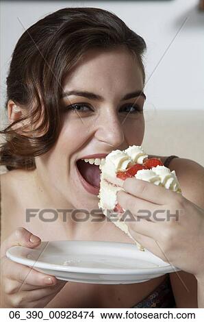 Woman FoodClose up of a woman wearing strappy taupe top eating a slice of fresh cream and strawberry gateau View Large Photo Image Picture - Woman FoodClose up of a woman wearing strappy taupe top eating a slice of fresh cream and strawberry gateau . Fotosearch
