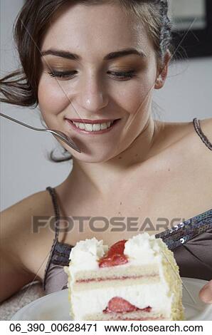 Woman FoodClose up of a woman wearing strappy taupe top reclining on a sofa eating a slice of fresh cream and strawberry gatea View Large Photo Image Stock Image - Woman FoodClose up of a woman wearing strappy taupe top reclining on a sofa eating a slice of fresh cream and strawberry gatea. Fotosearch