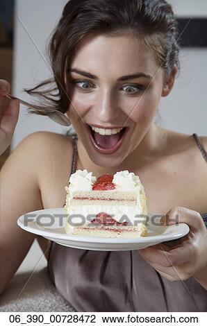 Woman FoodClose up of a woman wearing strappy taupe top reclining on a sofa eating a slice of fresh cream and strawberry gateau View Large Photo Image Stock Image - Woman FoodClose up of a woman wearing strappy taupe top reclining on a sofa eating a slice of fresh cream and strawberry gateau . Fotosearch