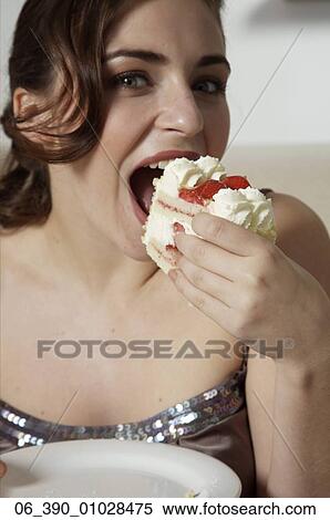Woman FoodWoman wearing strappy taupe top eating a slice of fresh cream and strawberry gateau View Large Photo Image Stock Photography - Woman FoodWoman wearing strappy taupe top eating a slice of fresh cream and strawberry gateau . Fotosearch