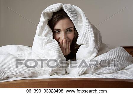 Woman in BedClose up of a woman in bed wrapped up in a white duvet with her hand over her mouth View Large Photo Image Stock Photo - Woman in BedClose up of a woman in bed wrapped up in a white duvet with her hand over her mouth . Fotosearch