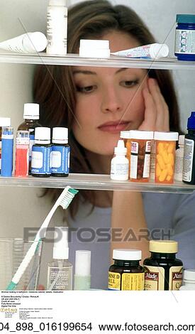 Picture -  Woman looking in bathroom / medicine cabinet. Fotosearch