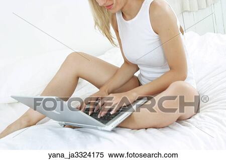 Woman sitting in bed using a laptop computer View Large Photo Image Stock Photography - Woman sitting in bed using a laptop computer. Fotosearch