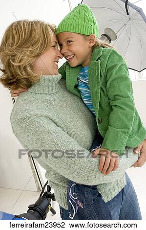 Woman wering a green sweater and a young girl wearing a green hat and a green jacket. The woman holds the girl View Large Photo Image Stock Image - Woman wering a green sweater and a young girl wearing a green hat and a green jacket. The woman holds the girl. Fotosearch