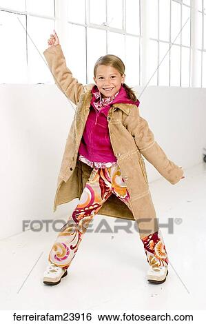 Young girl wearing a long coat standing in front of a window. View Large Photo Image Stock Photograph - Young girl wearing a long coat standing in front of a window. . Fotosearch