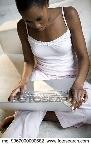 A young african american woman working on her laptop in her pajamas. View Large Photo Image Stock Image - A young african american woman working on her laptop in her pajamas.. Fotosearch