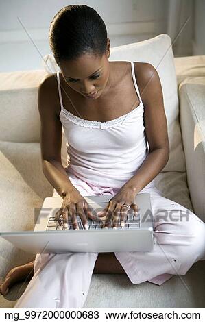 A young african american woman working on her laptop in her pajamas. View Large Photo Image Stock Image - A young african american woman working on her laptop in her pajamas.. Fotosearch