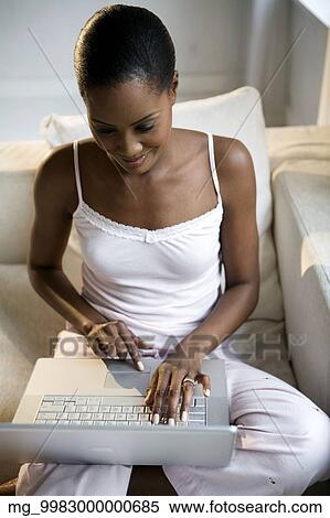 A young african american woman working on her laptop in her pajamas. View Large Photo Image Stock Photography - A young african american woman working on her laptop in her pajamas.. Fotosearch