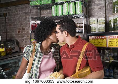 A young couple embraces while picking out groceries in a store. credit - RD / Retna Digital View Large Photo Image Stock Image - A young couple embraces while picking out groceries in a store. credit - RD / Retna Digital. Fotosearch