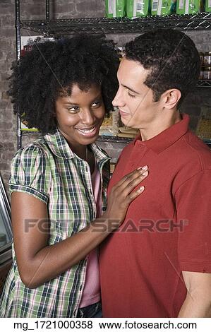 A young couple embraces while picking out groceries in a store. credit - RD / Retna Digital View Large Photo Image Stock Photo - A young couple embraces while picking out groceries in a store. credit - RD / Retna Digital. Fotosearch