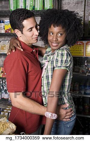 A young couple embraces while picking out groceries in a store. credit - RD / Retna Digital View Large Photo Image Stock Photo - A young couple embraces while picking out groceries in a store. credit - RD / Retna Digital. Fotosearch