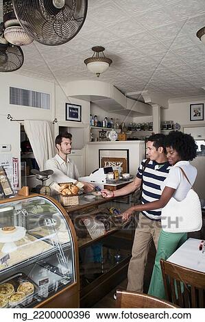 A young couple in their 20's or early 30's buy pastries at a bakery from a man behind a counter. September 1, 2006 credit - RD / Retna Digital View Large Photo Image Stock Photograph - A young couple in their 20's or early 30's buy pastries at a bakery from a man behind a counter. September 1, 2006 credit - RD / Retna Digital. Fotosearch