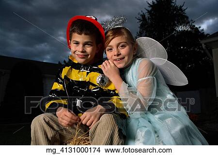 A young girl & boy out on halloween. He is wearing a fireman costume, equipped with hat & coat. The Girl is dressed as a fairy princess in a light blue gown, wings and a halo. They are outside sitting on a haystack playing. © Retna Digital / Retna Lt View Large Photo Image Picture - A young girl & boy out on halloween. He is wearing a fireman costume, equipped with hat & coat. The Girl is dressed as a fairy princess in a light blue gown, wings and a halo. They are outside sitting on a haystack playing. © Retna Digital / Retna Lt. Fotosearch