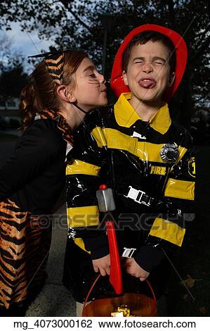 A young girl & boy out on halloween. She is dressed as a cat in a black unitard and tights with a animal print fur trim collar & skirt. She uses makeup to a cat noses and whiskers and costume ears. The Boy is wearing a fireman costume, equipped with ha View Large Photo Image Stock Image - A young girl & boy out on halloween. She is dressed as a cat in a black unitard and tights with a animal print fur trim collar & skirt. She uses makeup to a cat noses and whiskers and costume ears. The Boy is wearing a fireman costume, equipped with ha. Fotosearch