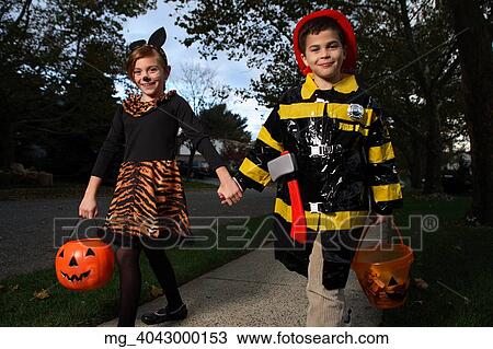 A young girl & boy walking down the sidewalk on a quest for more halloween candy. She is dressed as a cat in a black unitard and tights with a animal print fur trim collar and skirt. She uses makeup to a cat noses and whiskers and costume ears. The Boy View Large Photo Image Stock Image - A young girl & boy walking down the sidewalk on a quest for more halloween candy. She is dressed as a cat in a black unitard and tights with a animal print fur trim collar and skirt. She uses makeup to a cat noses and whiskers and costume ears. The Boy. Fotosearch