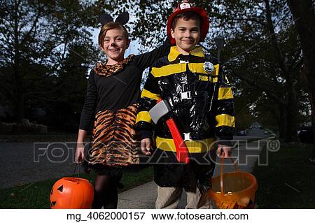 A young girl & boy walking down the sidewalk on a quest for more halloween candy. She is dressed as a cat in a black unitard and tights with a animal print fur trim collar and skirt. She uses makeup to a cat noses and whiskers and costume ears. The Boy View Large Photo Image Stock Photo - A young girl & boy walking down the sidewalk on a quest for more halloween candy. She is dressed as a cat in a black unitard and tights with a animal print fur trim collar and skirt. She uses makeup to a cat noses and whiskers and costume ears. The Boy. Fotosearch