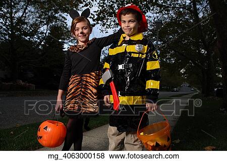 A young girl & boy walking down the sidewalk on a quest for more halloween candy. She is dressed as a cat in a black unitard and tights with a animal print fur trim collar and skirt. She uses makeup to a cat noses and whiskers and costume ears. The Boy View Large Photo Image Stock Photo - A young girl & boy walking down the sidewalk on a quest for more halloween candy. She is dressed as a cat in a black unitard and tights with a animal print fur trim collar and skirt. She uses makeup to a cat noses and whiskers and costume ears. The Boy. Fotosearch