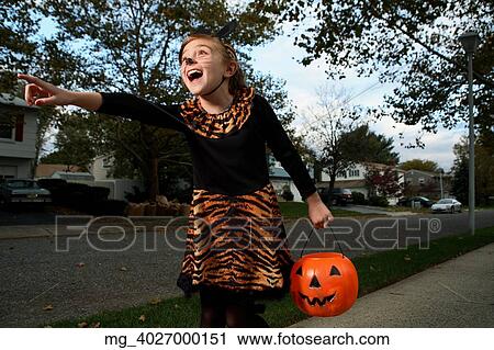 A young girl on the sidewalk on the quest for more halloween candy. She is dressed as a cat in a black unitard and tights with a animal print fur trim collar and skirt. She uses makeup to a cat noses and whiskers and costume ears. She is holding a pump View Large Photo Image Stock Image - A young girl on the sidewalk on the quest for more halloween candy. She is dressed as a cat in a black unitard and tights with a animal print fur trim collar and skirt. She uses makeup to a cat noses and whiskers and costume ears. She is holding a pump. Fotosearch
