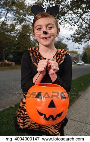 A young girl on the sidewalk on the quest for more halloween candy. She is dressed as a cat in a black unitard and tights with a animal print fur trim collar and skirt. She uses makeup to a cat noses and whiskers and costume ears. She is holding a pump View Large Photo Image Stock Photo - A young girl on the sidewalk on the quest for more halloween candy. She is dressed as a cat in a black unitard and tights with a animal print fur trim collar and skirt. She uses makeup to a cat noses and whiskers and costume ears. She is holding a pump. Fotosearch