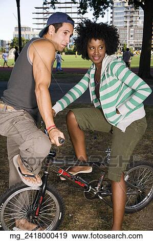 A young man and a young woman on a bike both in their 20's meet in the park and talk. September 1, 2006 credit - RD / Retna Digital View Large Photo Image Stock Photo - A young man and a young woman on a bike both in their 20's meet in the park and talk. September 1, 2006 credit - RD / Retna Digital. Fotosearch