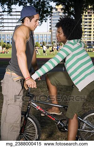 A young man and a young woman on a bike both in their 20's meet in the park and talk. September 1, 2006 credit - RD / Retna Digital View Large Photo Image Stock Photography - A young man and a young woman on a bike both in their 20's meet in the park and talk. September 1, 2006 credit - RD / Retna Digital. Fotosearch