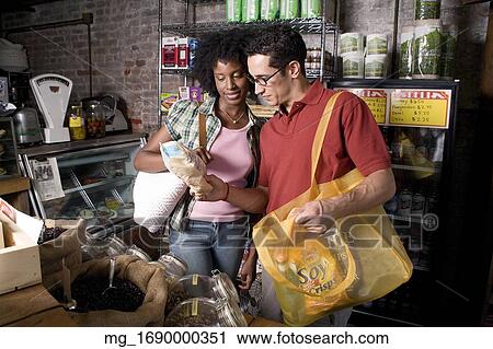 Stock Image - A young man and woman picks out groceries in a store. credit - RD / Retna Digital. Fotosearch