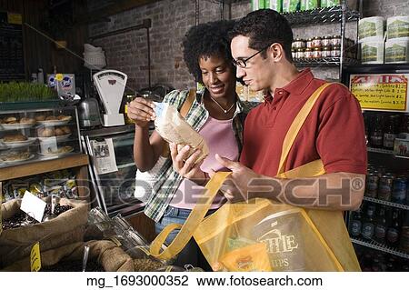 Stock Image - A young man and woman picks out groceries in a store. credit - RD / Retna Digital. Fotosearch