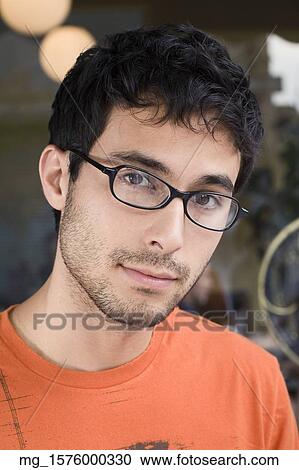 A young man in glasses and an orange shirt outside a shop. September 1, 2006 credit - RD / Retna Digital View Large Photo Image Stock Image - A young man in glasses and an orange shirt outside a shop. September 1, 2006 credit - RD / Retna Digital. Fotosearch