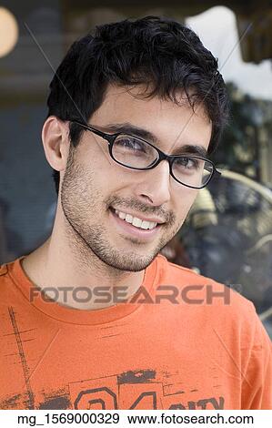 A young man in glasses and an orange shirt outside a shop. September 1, 2006 credit - RD / Retna Digital View Large Photo Image Stock Photo - A young man in glasses and an orange shirt outside a shop. September 1, 2006 credit - RD / Retna Digital. Fotosearch