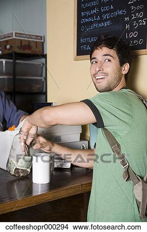 A young man wearing a backpack buys a drink from a coffee shop. December 30, 2006 credit - RD / Retna Digital View Large Photo Image Picture - A young man wearing a backpack buys a drink from a coffee shop. December 30, 2006 credit - RD / Retna Digital. Fotosearch