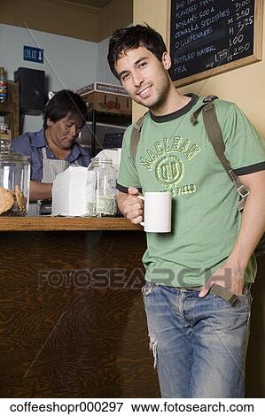 A young man wearing a backpack buys a drink from a coffee shop. December 30, 2006 credit - RD / Retna Digital View Large Photo Image Stock Photo - A young man wearing a backpack buys a drink from a coffee shop. December 30, 2006 credit - RD / Retna Digital. Fotosearch
